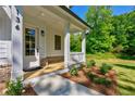 Inviting front porch with white columns, wood decking, and landscaping that adds to the home's curb appeal at 136 Beutell St, Norcross, GA 30071