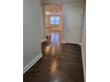 Hallway leading to living spaces with gleaming hardwood floors and neutral paint at 8265 Village Pl, Suwanee, GA 30024