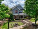 Two-story home featuring stone accents, blue siding, landscaped front yard, and a charming covered front porch at 207 Harmony Lake Dr, Canton, GA 30115