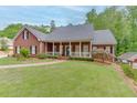 Inviting brick home with a classic front porch, manicured lawn, and mature landscaping at 4355 Old Hamilton Mill Rd, Buford, GA 30518