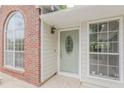 Inviting front entrance with decorative sage door, sidelight, transom window, and brick accent wall at 4565 English Oaks Ln, Lilburn, GA 30047