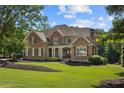 Beautiful brick home featuring a well-manicured lawn and charming architectural details at 13037 Overlook Pass, Roswell, GA 30075