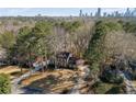 Aerial view of a stunning two-story brick home nestled in a wooded area, with a city skyline in the distance at 725 Glengary Ne Way, Atlanta, GA 30342