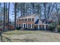 This exterior shot captures a classic brick home with black shutters and a well-maintained lawn and mature trees at 725 Glengary Ne Way, Atlanta, GA 30342