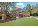 Beautiful brick home showcasing mature trees, a well-maintained lawn, and lovely curb appeal at 1025 Saint Marks Walk, Suwanee, GA 30024