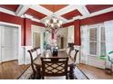 Formal dining room showcasing tray ceiling, hardwood floors, large windows, and elegant chandelier and dining set at 2041 Democracy Dr, Buford, GA 30519