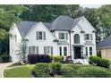 Beautiful white home with grey shutters, a well-maintained lawn, and an attached garage, offering ample space at 310 Hillpine Dr, Woodstock, GA 30189