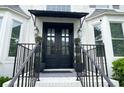 Elegant double front doors with a stylish black awning and decorative potted plants, creating a welcoming entrance at 310 Hillpine Dr, Woodstock, GA 30189