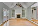 Bright living room featuring a vaulted ceiling, fireplace with built-in bookshelves, and beautiful hardwood floors and French doors at 261 Township Dr, Hiram, GA 30141