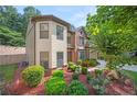 Beautiful exterior view of two story home surrounded by lush landscaping, flowering bushes and a large shade tree at 1736 Dylan Pl, Lawrenceville, GA 30043