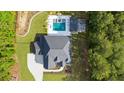 An aerial view of a backyard featuring a pool, spa, and a covered patio, surrounded by mature trees at 2400 Worth Ave, Loganville, GA 30052