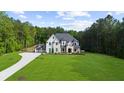 Expansive front yard with a winding driveway leading to a stunning two-story home surrounded by lush trees at 2400 Worth Ave, Loganville, GA 30052