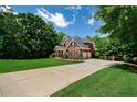 Long concrete driveway leading to a brick home with attached garage, lush lawn and mature trees at 7251 Bluewater Ln, Douglasville, GA 30135