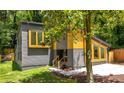 View of the home's modern design with gray siding, wooden window trim, and well-maintained lawn at 2155 Venetian Sw Dr, Atlanta, GA 30311