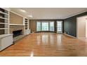 Spacious living room featuring a brick fireplace, built-in shelving, large windows, and gleaming hardwood floors at 295 Lakemont Dr, Roswell, GA 30075