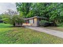 Quaint single-story brick home featuring mature trees, a well-manicured lawn, and a welcoming red front door at 4029 Moffat Ct, Decatur, GA 30035