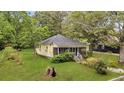 Cozy cottage-style home with a screened front porch, surrounded by lush greenery, on a well-maintained lawn at 204 Morris St, Palmetto, GA 30268