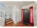 Bright entryway featuring hardwood floors, stair lift, and red curtains flanking a black front door at 701 Fir Chase, Fairburn, GA 30213