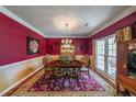 Elegant dining room with rich red walls, crown molding, and a large window for natural light at 12 Blackfoot Trl, Sharpsburg, GA 30277