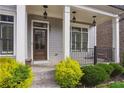 Inviting front porch with decorative columns, a dark wood front door, and colorful landscaping at 5981 Brundage Ln, Norcross, GA 30071