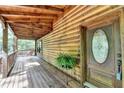 Inviting log home featuring a covered porch with an oval glass front door and wooded view at 2864 Winder Hwy, Dacula, GA 30019