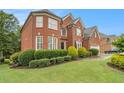 Charming brick home with manicured landscaping and a lush green lawn at 4045 Bonnett Creek Ln, Hoschton, GA 30548