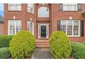 Inviting front entrance with a black door, brick steps and manicured bushes at 4045 Bonnett Creek Ln, Hoschton, GA 30548