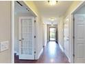 Bright hallway featuring hardwood floors, neutral walls, and doors with contrasting white trim at 2058 Bonneville Ln, Powder Springs, GA 30127