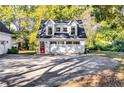 Detached three-car garage featuring carriage doors, a red entry door, and upper story windows at 965 Sundew Se Dr, Conyers, GA 30013