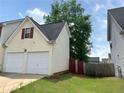 Exterior view of attached two car garage with white doors and lush green yard in daytime at 130 Hazelhurst Dr, Covington, GA 30016