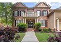 Charming brick home featuring a covered entrance, lush landscaping, and a manicured lawn with an inviting walkway at 4840 Spring Park Cir, Suwanee, GA 30024