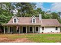 Inviting gray home featuring a covered front porch, well-manicured lawn, and mature trees at 60 Valley Rd, Covington, GA 30016