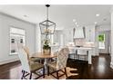 Open dining area with modern light fixture, adjacent to a kitchen with white cabinetry and island seating at 3481 Landen Pine Ne Ct, Atlanta, GA 30305