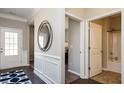 Hallway view showcases white wainscoting, artful mirror, leading to a full bathroom with tub and shower at 655 Blackshear Trl, Temple, GA 30179