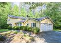 Two-story house with an attached garage and a driveway, surrounded by trees and greenery at 2037 Cliffton Ter, Snellville, GA 30039