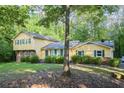 View of yellow, two-story home with well-kept lawn and mature trees offering shade and privacy at 2037 Cliffton Ter, Snellville, GA 30039