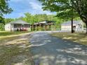 Home with covered parking and an outbuilding next to a driveway surrounded by lush, mature trees at 505 Sandhill Hickory Level Rd, Carrollton, GA 30116