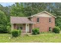 Charming two-story brick home featuring a covered front porch and red shutters surrounded by lush greenery at 1576 King Mill Rd, Mcdonough, GA 30252