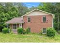 Charming two-story brick home featuring a covered front porch and red shutters surrounded by lush greenery at 1576 King Mill Rd, Mcdonough, GA 30252