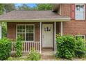 Inviting front porch of a brick home, featuring a white railing, natural light, and freshly trimmed bushes at 1576 King Mill Rd, Mcdonough, GA 30252
