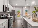 Open kitchen featuring stainless appliances, white cabinetry, island and an exterior access door at 5615 Hislop Ln # 82, Mableton, GA 30126