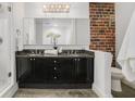 Modern bathroom featuring a double vanity, granite countertop, and exposed brick accent wall at 204 Walker Sw St # 319, Atlanta, GA 30313