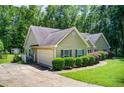 Exterior shot of the home and its garage, complemented by lush greenery and a driveway at 414 Pamela Ct, Mcdonough, GA 30252