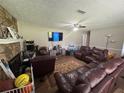 Comfortable living room featuring a stone fireplace, ceiling fan, and plush leather seating at 4284 Village Green W Cir, Conyers, GA 30013