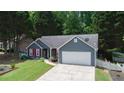 Charming blue home with red shutters, green lawn, and a two-car garage nestled among lush green trees at 5742 Riverside Walk Dr, Sugar Hill, GA 30518