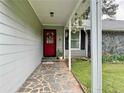 Inviting front porch with stone tiling, a red front door, and hanging potted plants at 11072 Shannon Cir, Hampton, GA 30228