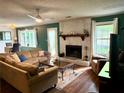 Cozy living room featuring a stone fireplace, dark wood floors, and ample natural light at 11072 Shannon Cir, Hampton, GA 30228