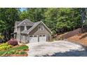Exterior view of a home with a two-car garage, extensive driveway, and mature trees surrounding the property at 4320 Oklahoma Nw Way, Kennesaw, GA 30152
