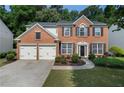 Charming red brick two-story home with a two-car garage and manicured front lawn at 4321 Sugar Maple Chase Nw, Acworth, GA 30101