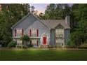 Charming two-story home with a well-manicured lawn, stone accents, red shutters and a bright red front door at dusk at 4638 Arrow Wind Dr, Powder Springs, GA 30127
